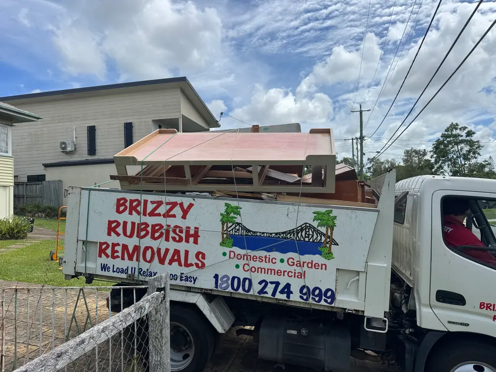 Brizzy Rubbish Removals truck loaded with furniture outside a Queenslander home in Morningside