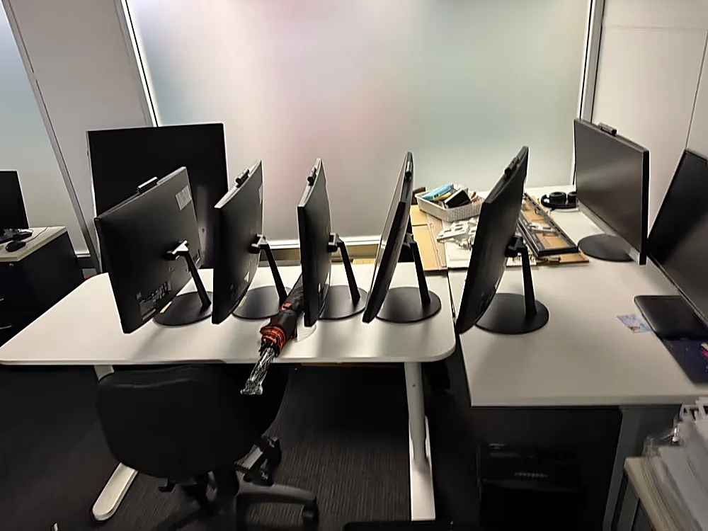 Row of unplugged computer monitors on a stripped office desk during a commercial cleanout in Brisbane