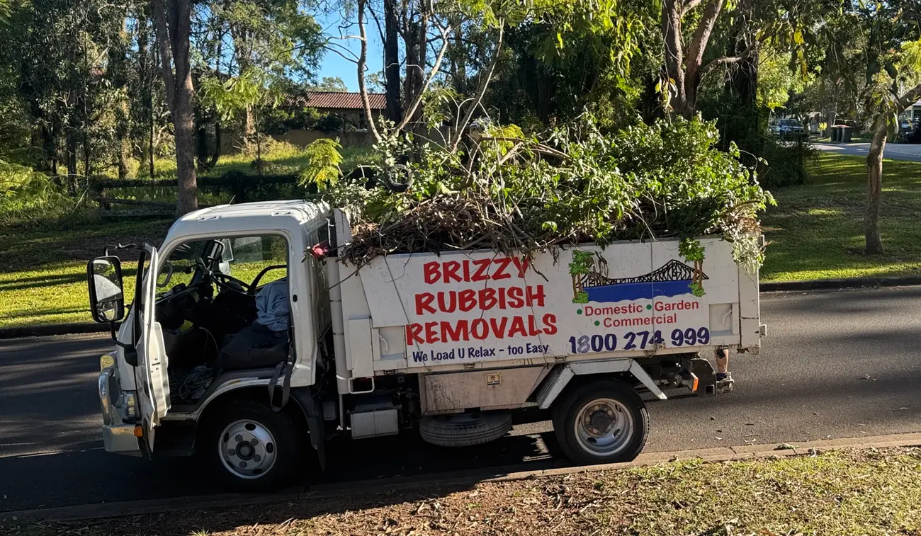 Brizzy Rubbish Removals truck loaded above the sides with branches and garden waste on a Brisbane street